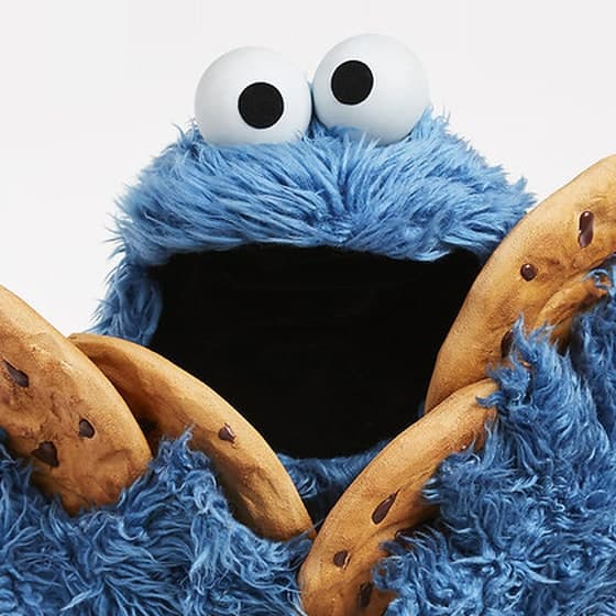 Het Koekiemonster, met zijn mond open en een handvol koekjes.
