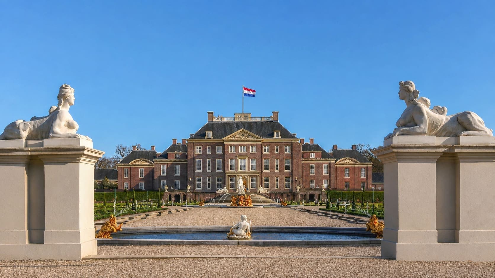 Paleis Het Loo bij Apeldoorn, gezien vanuit de tuin met fonteinen, met op de voorgrond twee stenen sfinxen op pilaren.