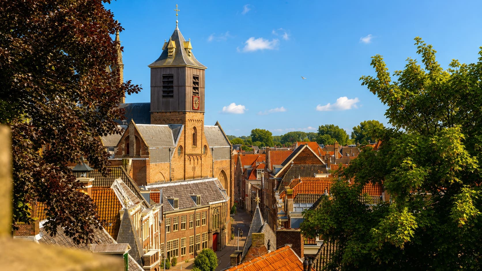 Uitzicht over oude daken met een bakstenen kerk en een houten klokkentoren met een gouden uurwerk.